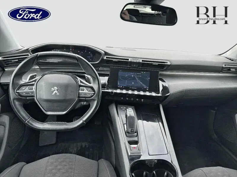 Vue intérieure avant du tableau de bord et volant cuir noir d'une Peugeot 508 SW gris Platinium avec écran tactile et commandes intégrées.