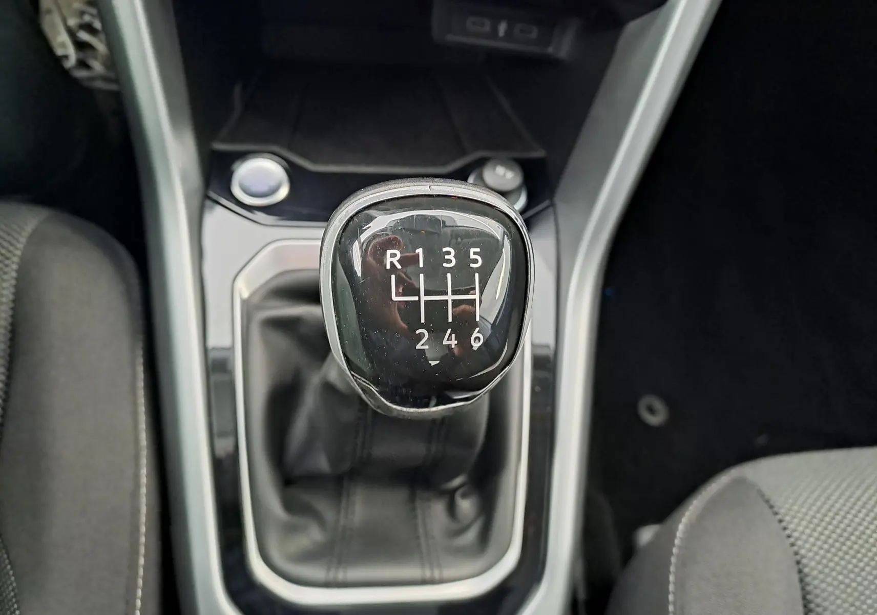 Vue rapprochée du levier de vitesse manuel noir du Volkswagen T-Roc 2022, entouré de garnitures grises et sièges tissu.