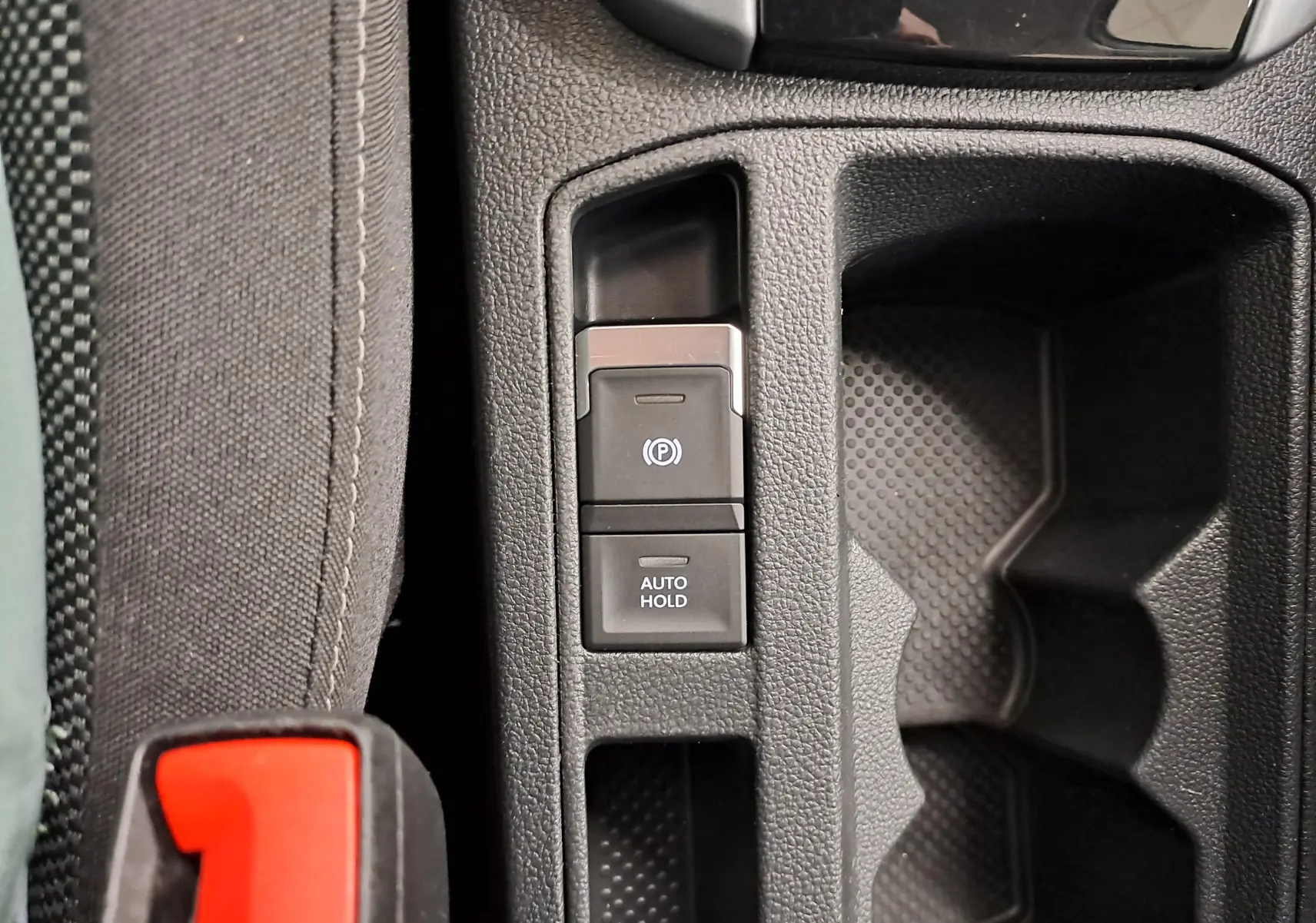 Gros plan sur la console centrale du Volkswagen T-Roc 2022, montrant les boutons frein à main électronique et Auto Hold.