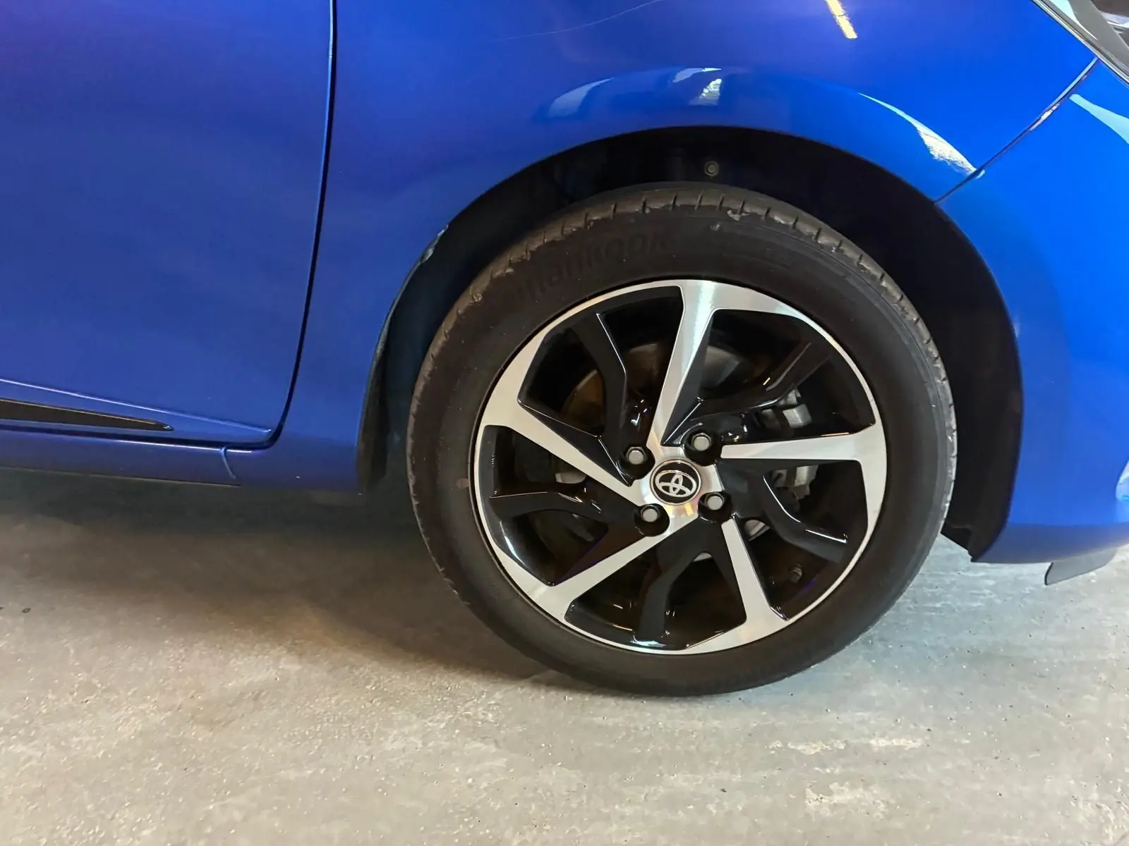 Gros plan sur la roue avant droite et la carrosserie bleue d'une Toyota Yaris 1.5 Hybrid Collection de 2020.