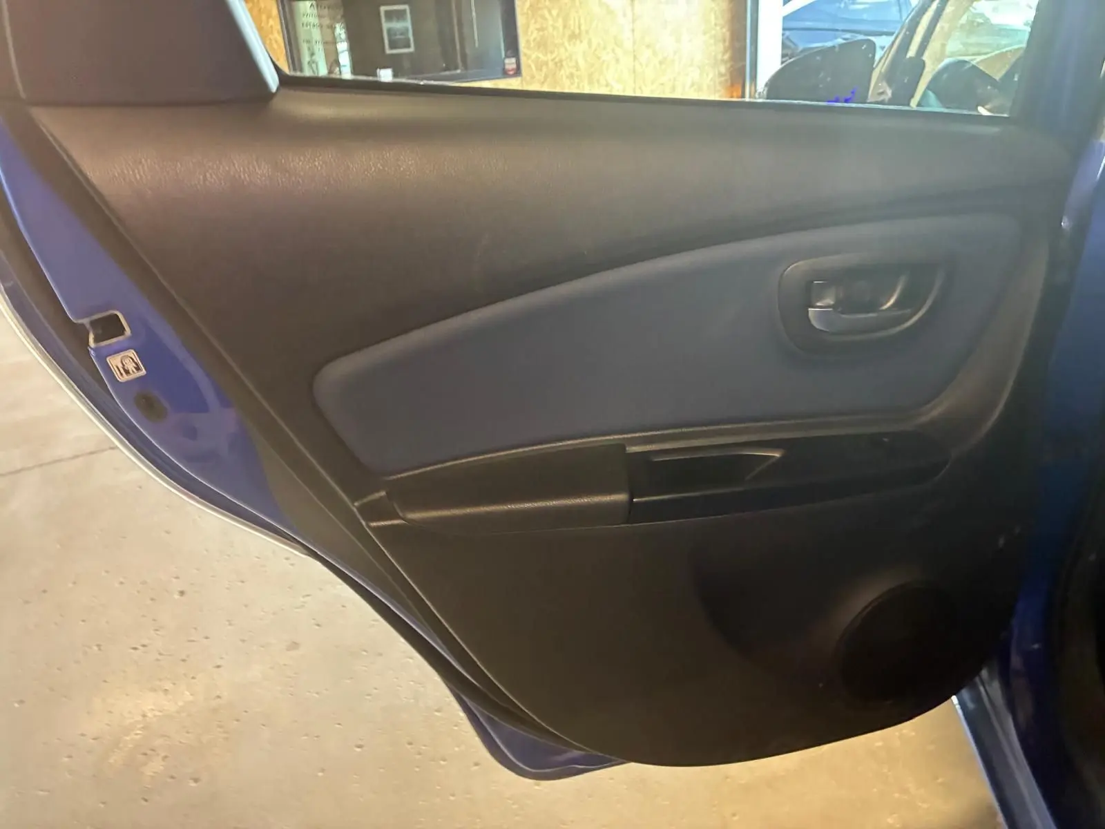 Vue intérieure sur la porte arrière gauche bleu de la Toyota Yaris 2020, avec panneau noir et poignée intégrée.