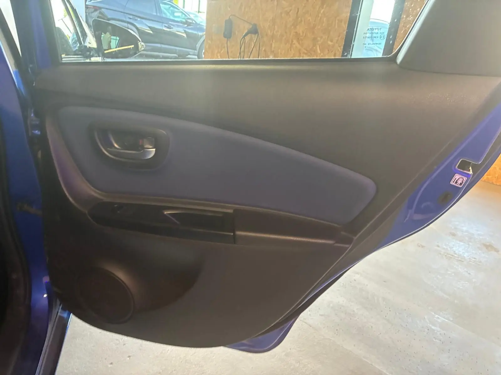 Vue intérieure de la porte arrière gauche bleu foncé d'une Toyota Yaris hybride 2020, avec panneau noir et tissu bleu.