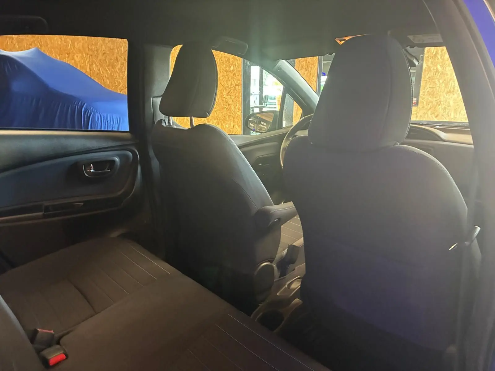 Vue intérieure arrière de la Toyota Yaris hybride 2020, sièges en tissu noir et tableau de bord partiellement visible.