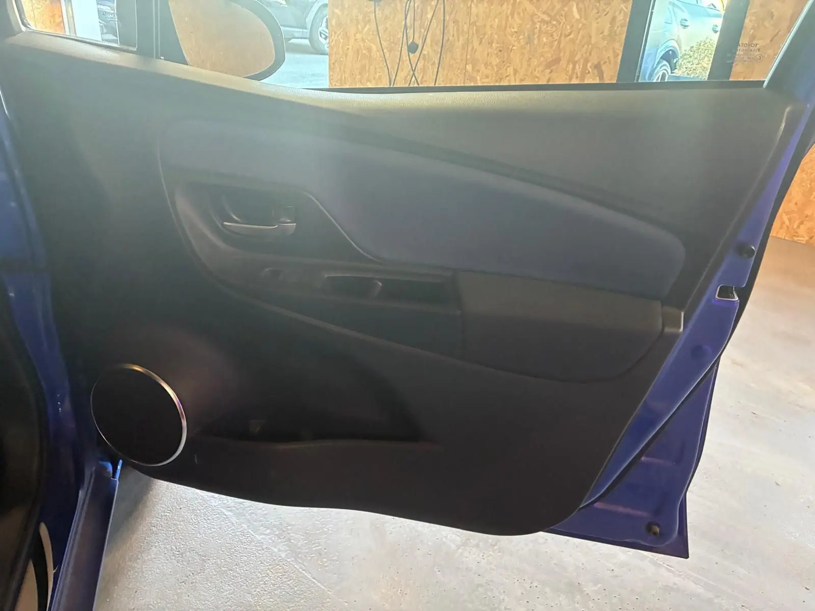 Vue intérieure de la porte avant gauche bleue d'une Toyota Yaris 2020, avec haut-parleur rond et poignée noire.