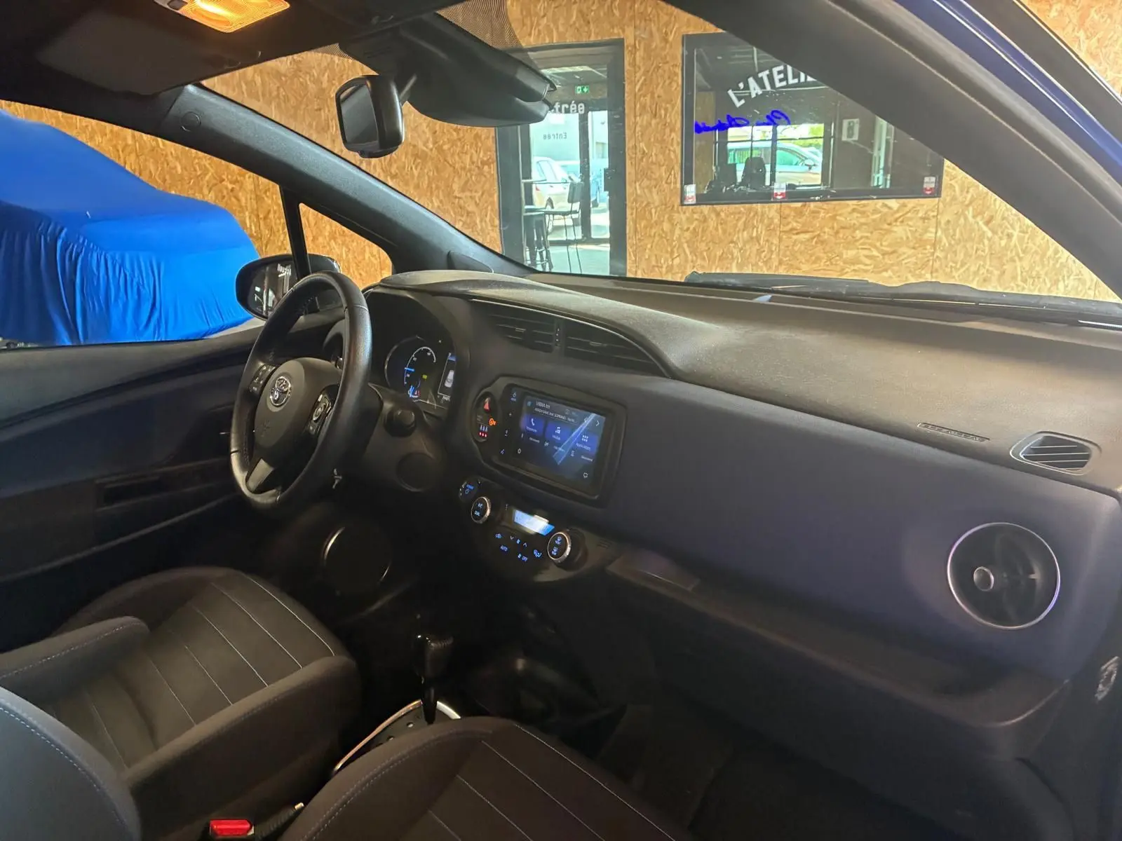 Vue intérieure côté conducteur de la Toyota Yaris 2020, tableau de bord noir avec écran tactile et volant multifonction.