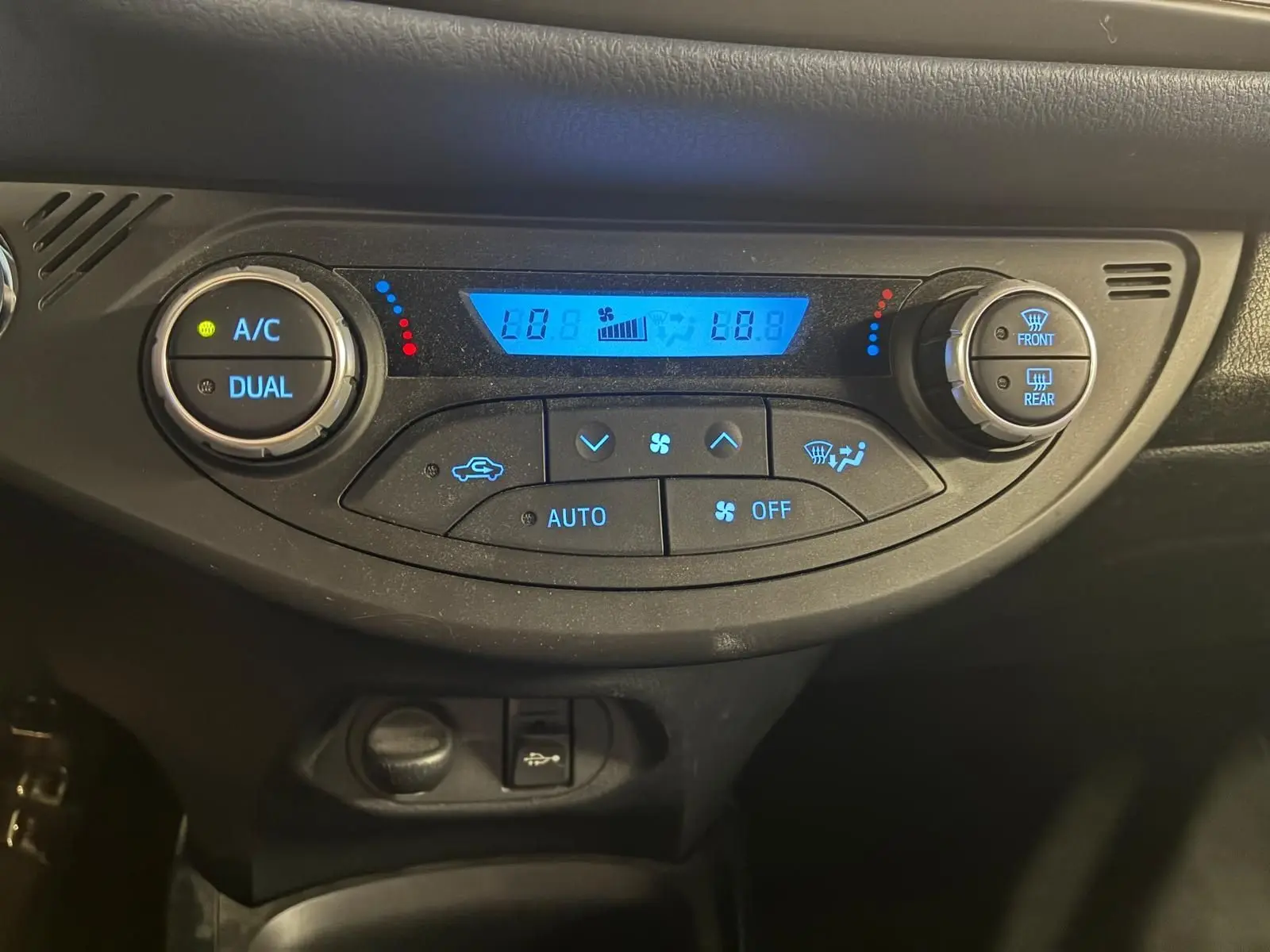 Panneau de commande de climatisation digitale bleu dans une Toyota Yaris hybride 2020, vue frontale rapprochée.