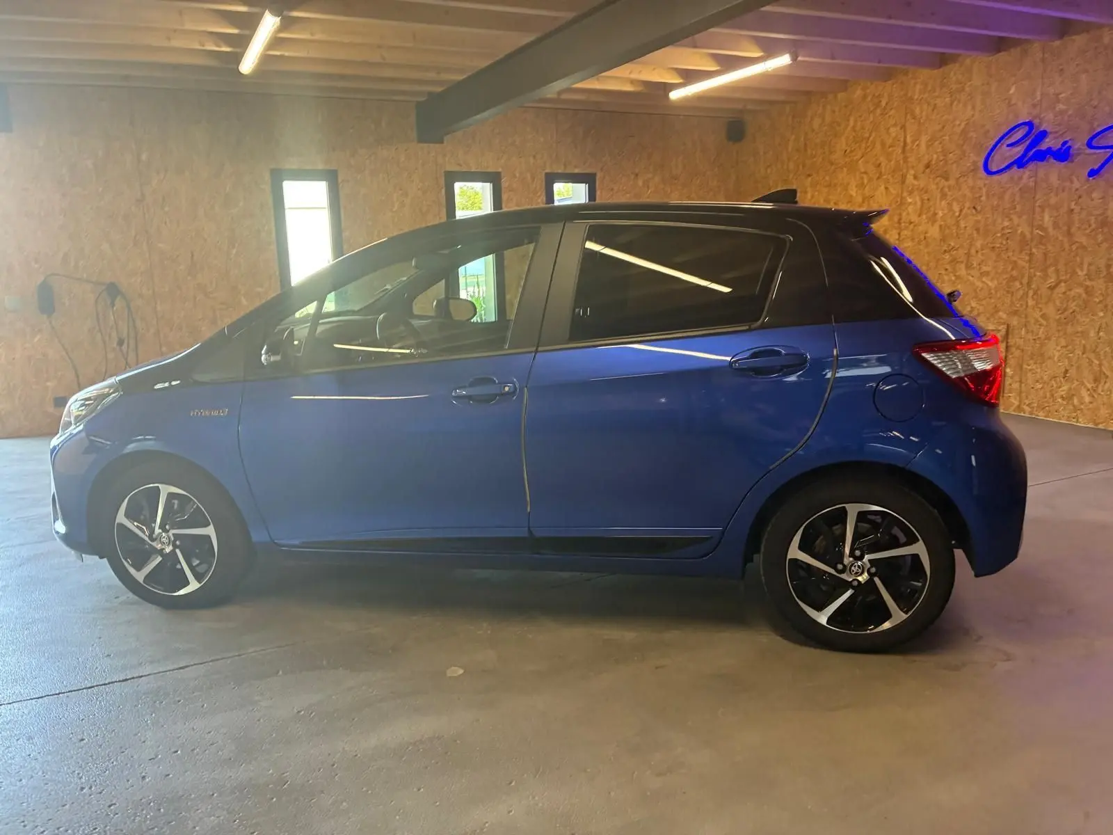 Profil côté gauche de la Toyota Yaris hybride bleue 5 portes, avec toit noir et jantes alliage distinctives.