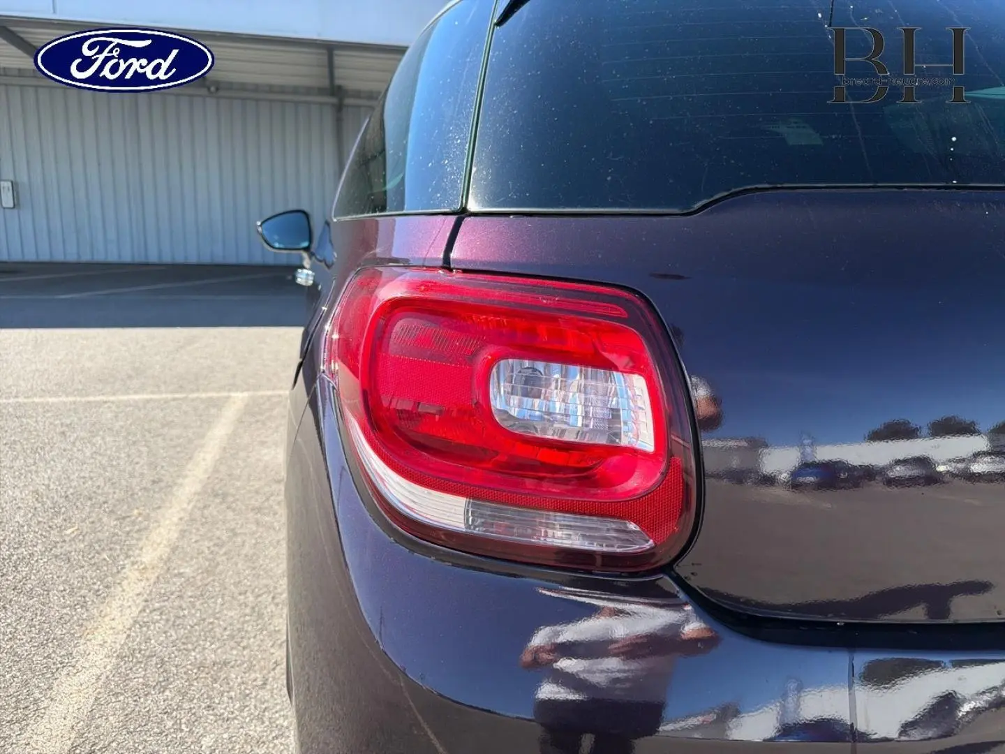 Feu arrière gauche en gros plan d'une Citroën DS3 rouge Rubi 2014, avec reflet sur la carrosserie brillante.