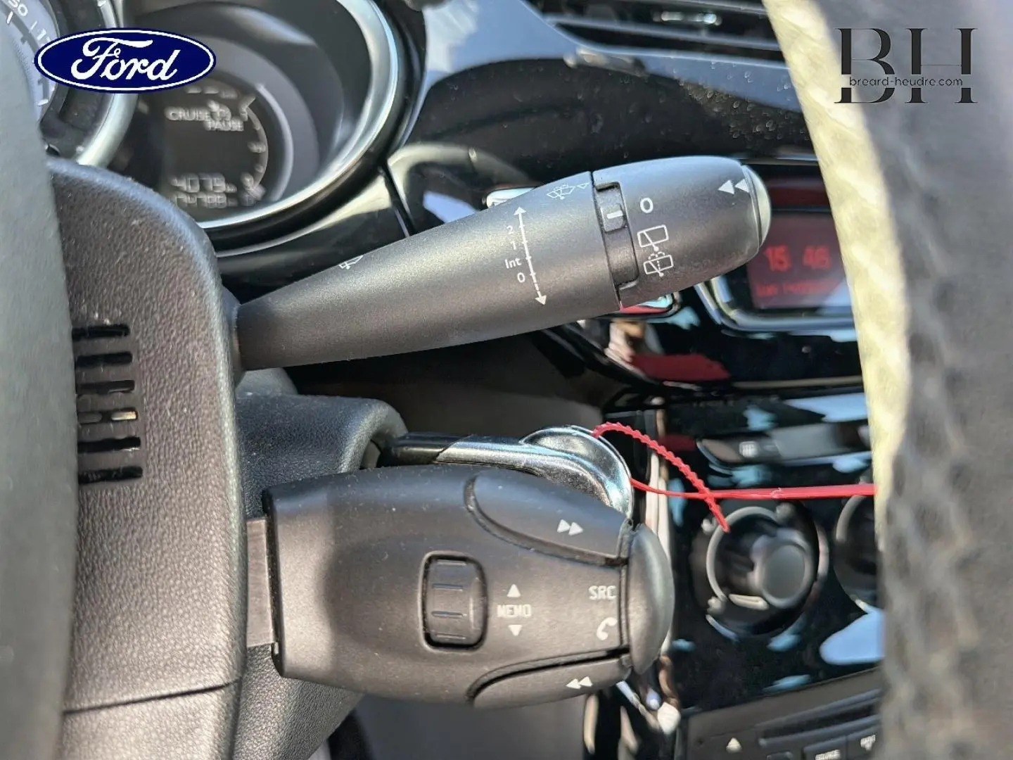 Gros plan sur la commande au volant et le commodo d’essuie-glace d’une Citroën DS3 rouge Rubi, intérieur noir.
