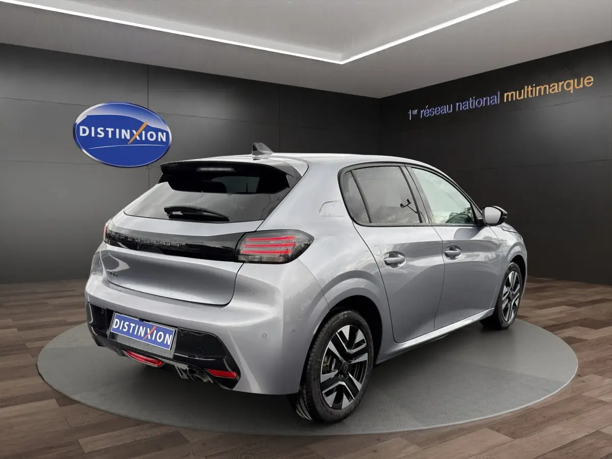 Vue 3/4 arrière droite d'une Peugeot 208 gris clair 2025 avec feux arrière LED et jantes alliage distinctives.