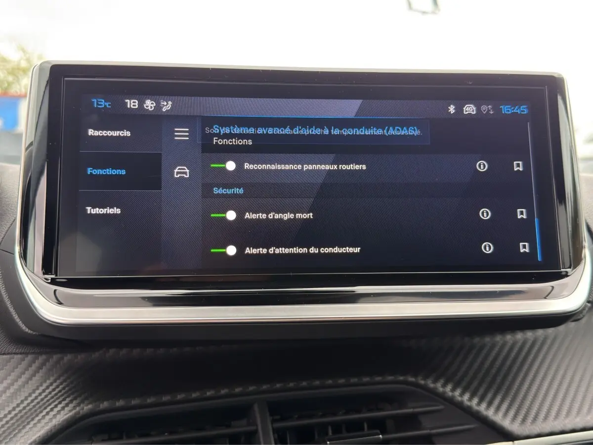 Écran tactile central affichant les réglages d’aides à la conduite dans l’habitacle d’une Peugeot 208 gris clair.