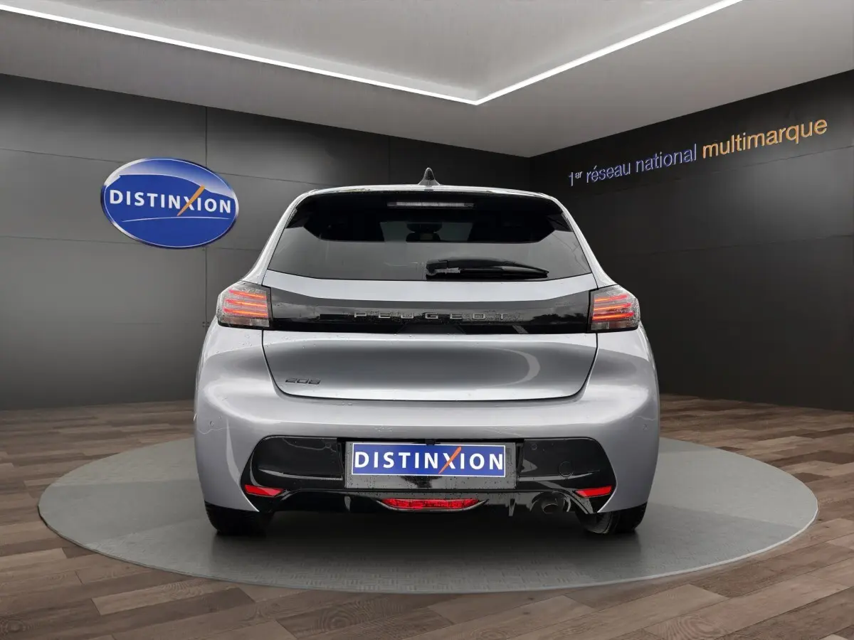 Vue arrière d'une Peugeot 208 gris clair 2025 avec feux LED et logo distinctif sur fond noir.