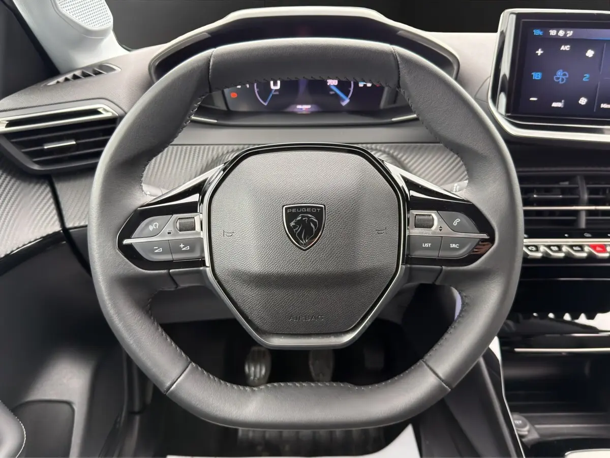 Vue rapprochée du volant cuir multifonctions de la Peugeot 208 2025 avec tableau de bord et écran tactile.