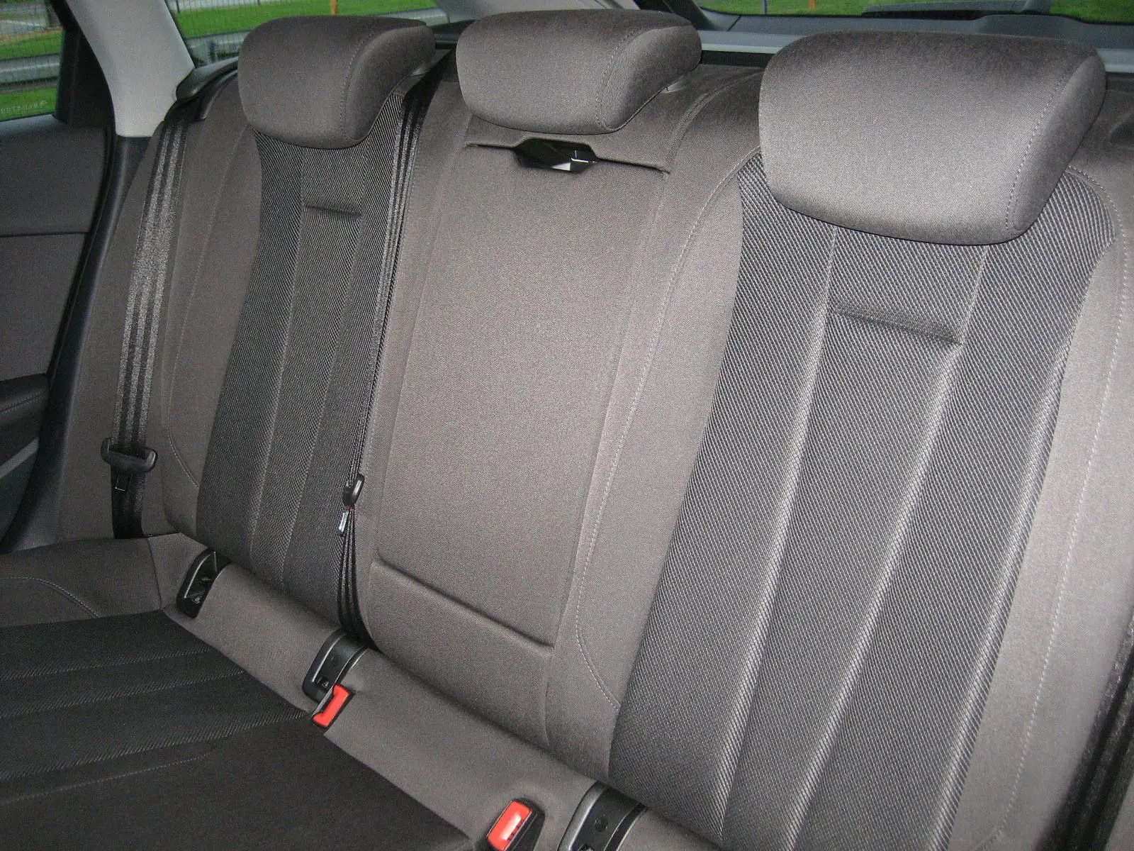 Vue rapprochée des sièges arrière en tissu gris de l'Audi A4 Avant 3.5 TDI 2022, avec appuie-têtes et ceintures visibles.