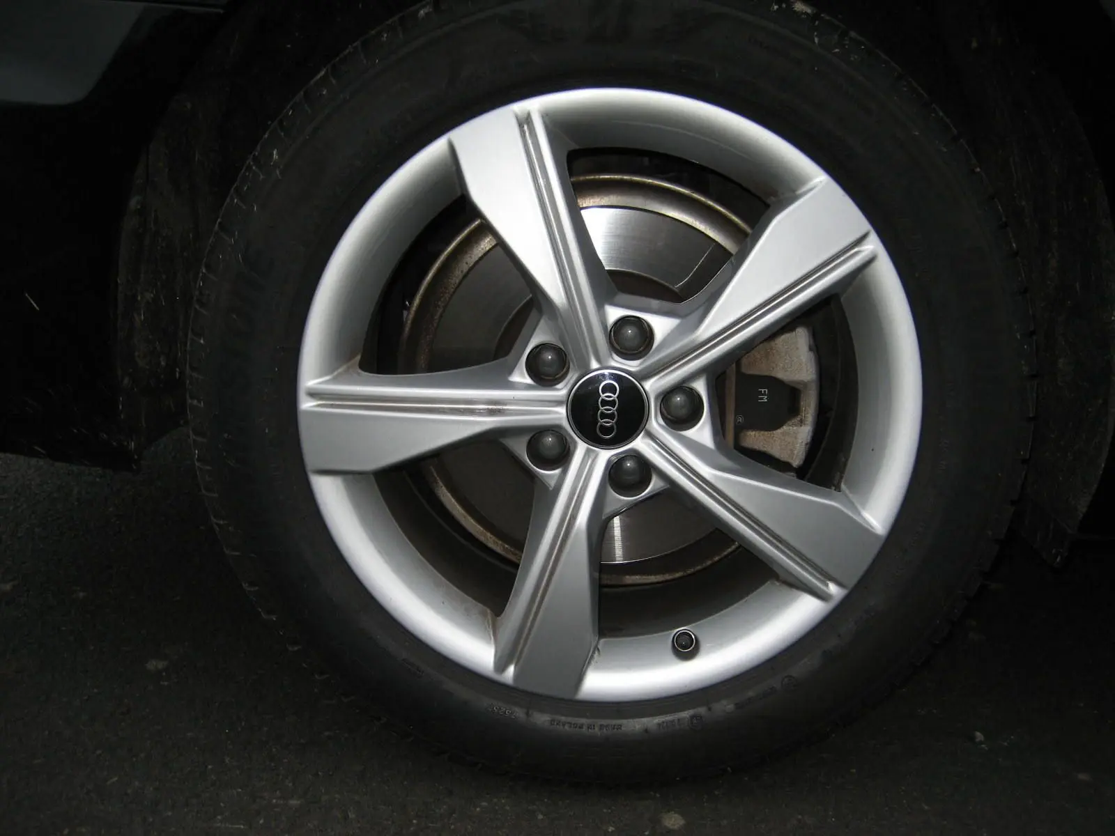 Gros plan sur la jante argentée de l'Audi A4 Avant 3.5 TDI 163 S Tronic Design noire, mettant en valeur le logo Audi central.