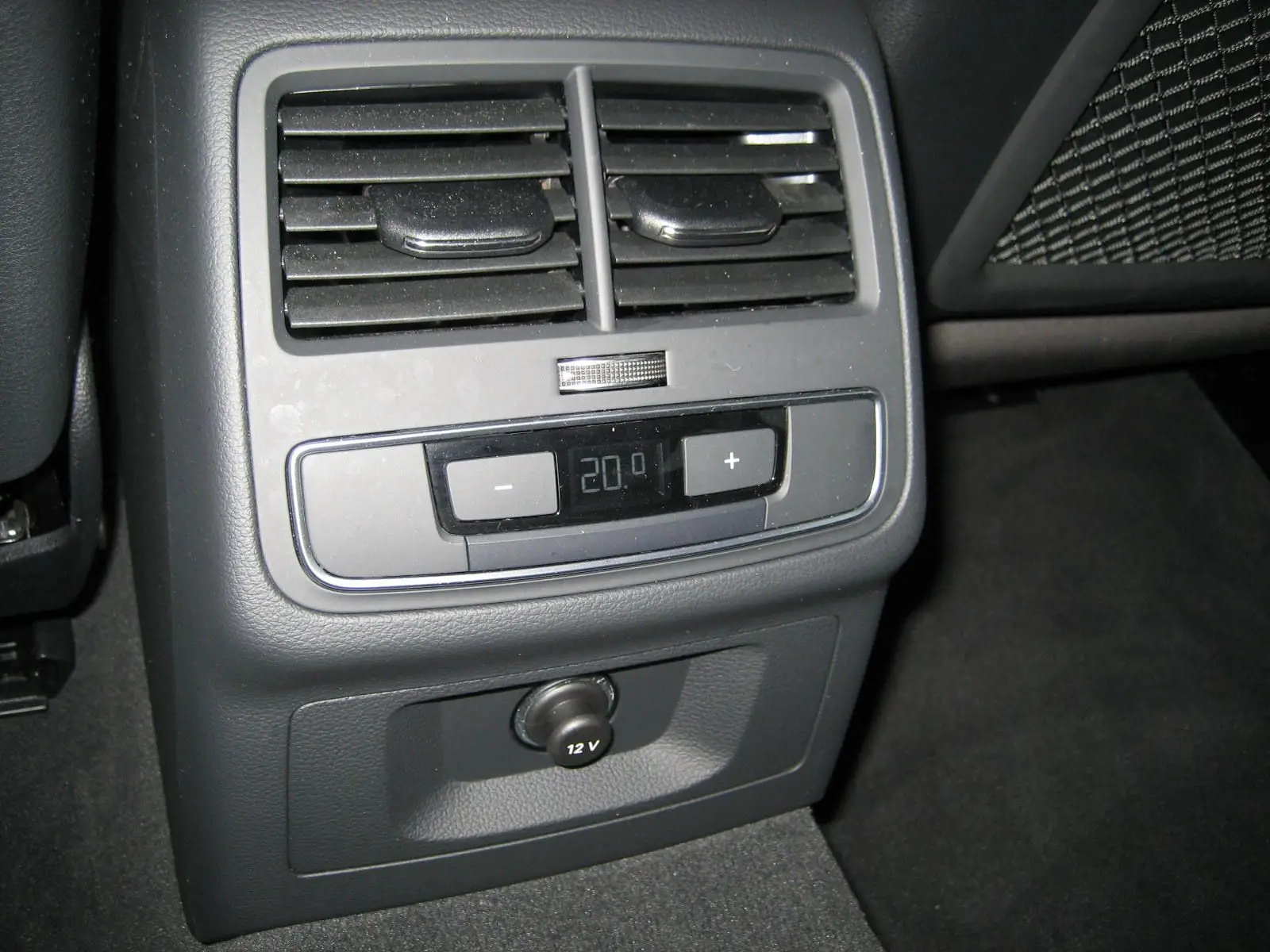 Vue rapprochée de la commande de climatisation arrière et prise 12V dans l'Audi A4 Avant noire 2022.