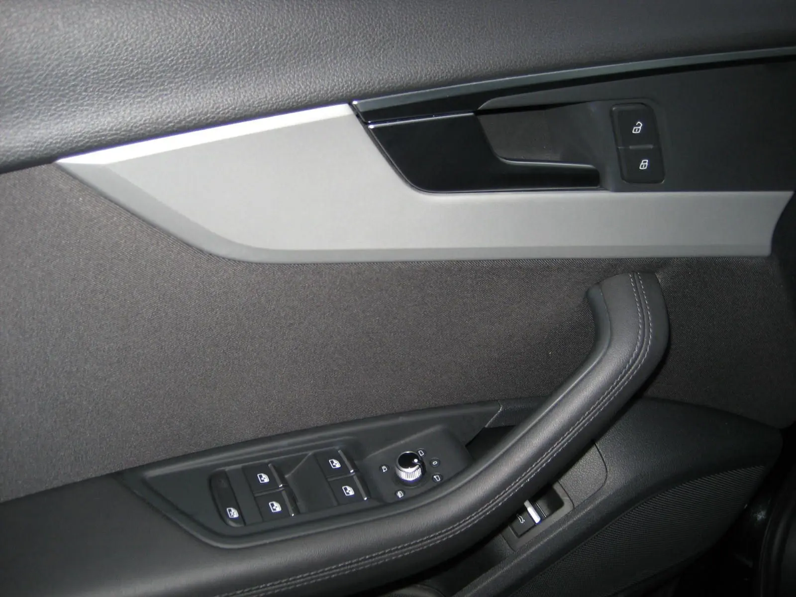 Gros plan sur la porte intérieure côté conducteur de l'Audi A4 Avant noire, montrant les commandes de vitres et de verrouillage.