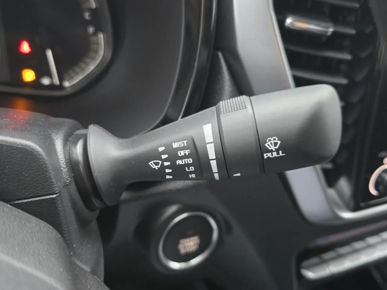 Gros plan sur la commande d’essuie-glace du tableau de bord noir d’un Isuzu D-MAX orange métallisé 2025.