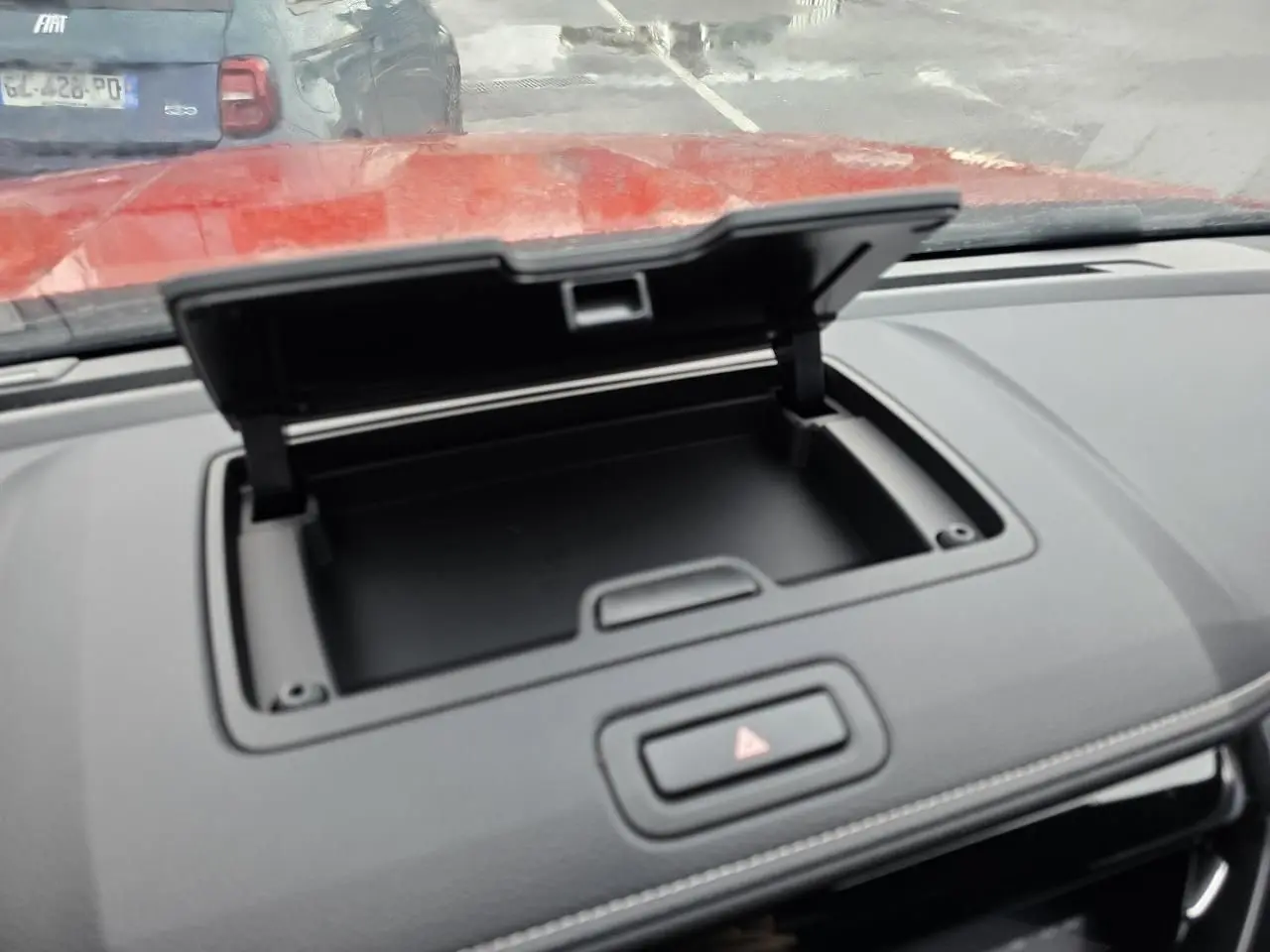 Détail de la console centrale ouverte du pick-up Isuzu D-MAX orange métal, avec bouton de signalisation au centre.