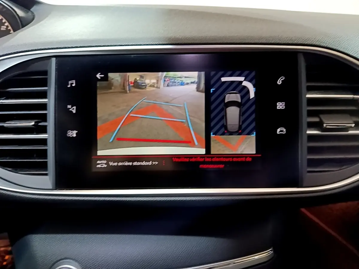 Écran tactile central de la Peugeot 308 GT Line blanc montrant l’aide au stationnement arrière avec caméra et capteurs.