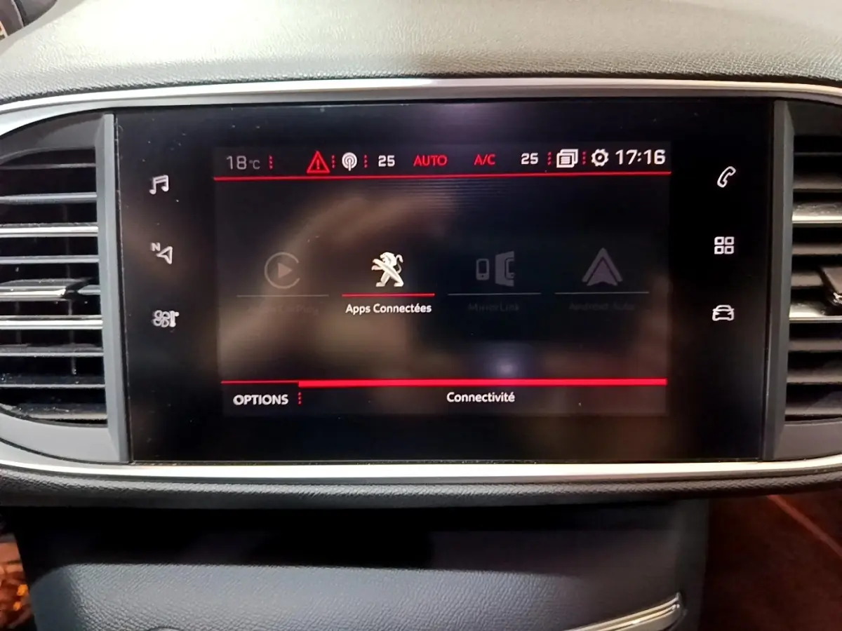 Écran tactile central affichant les applications connectées dans le tableau de bord d'une Peugeot 308 blanche.
