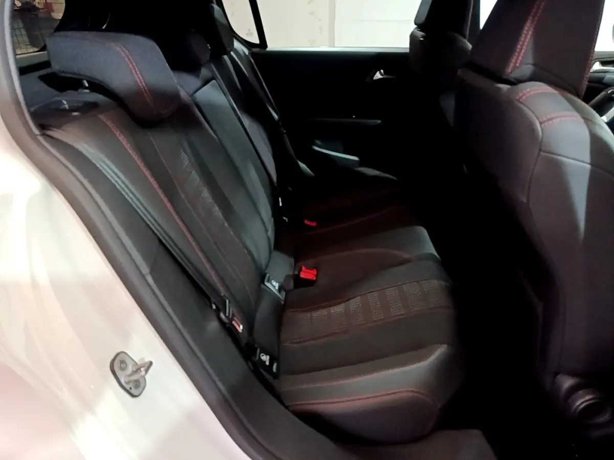 Vue côté gauche des sièges arrière noirs avec surpiqûres rouges d'une Peugeot 308 blanche de 2019.