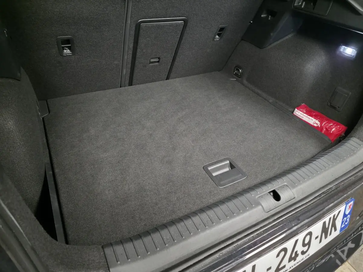 Coffre ouvert vu de l'arrière d'un CUPRA Formentor gris, avec plancher plat et trappe à skis visible.