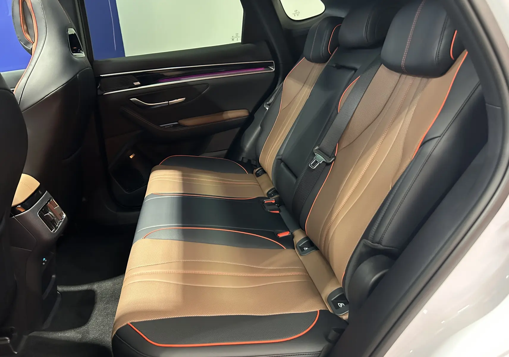Vue intérieure arrière côté droit du BYD SEAL U avec sièges en cuir marron et noir soulignés de surpiqûres orange.