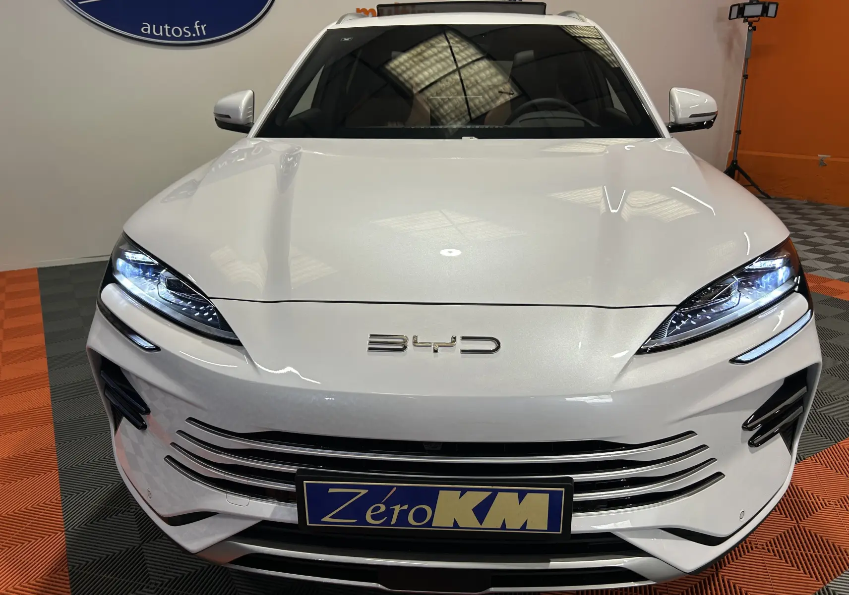 Vue frontale d'une BYD SEAL U blanche nacrée avec phares LED allumés et calandre horizontale distinctive.