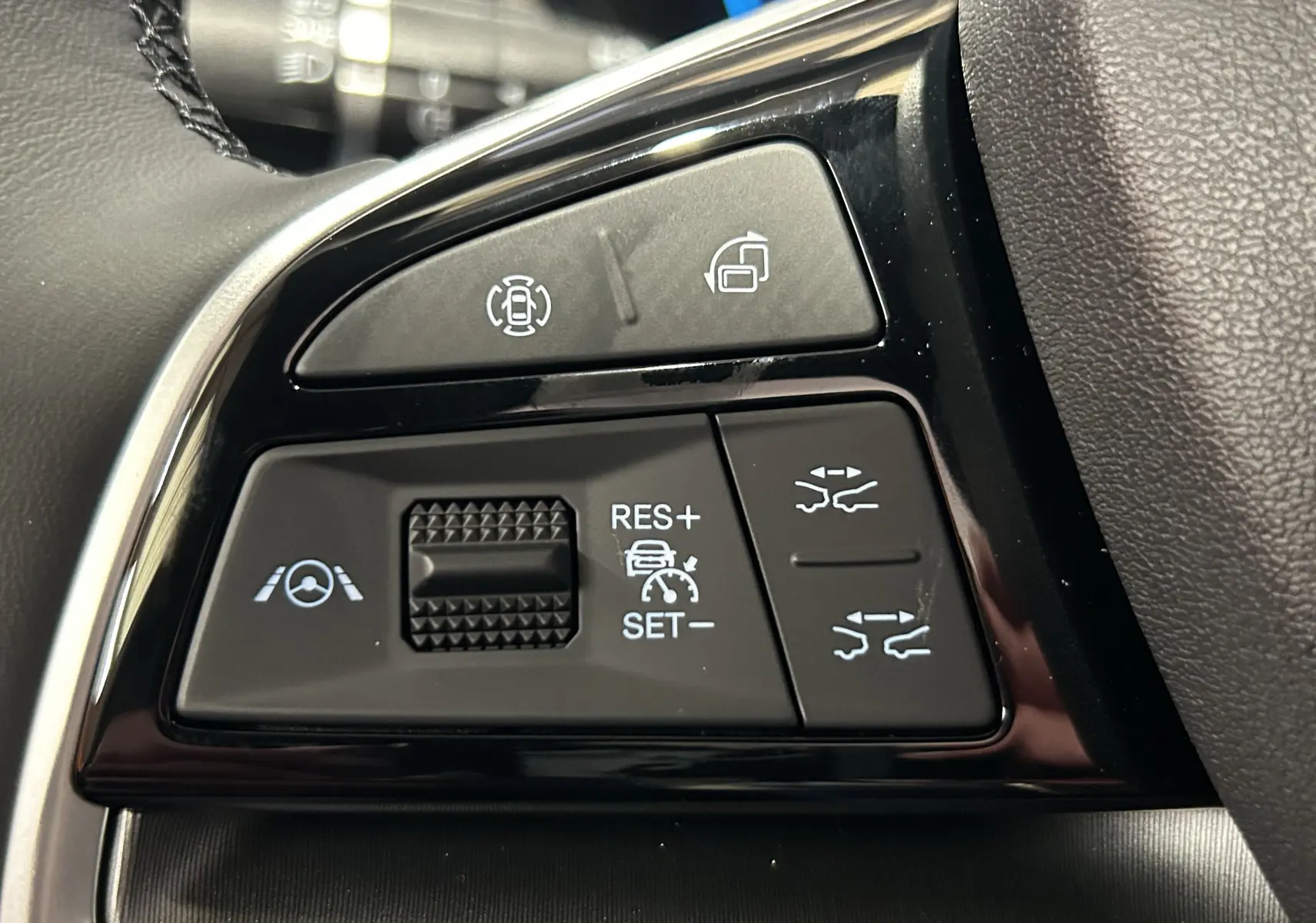 Gros plan sur les commandes noires du volant du BYD SEAL U 2025, avec boutons de régulateur et aides à la conduite.