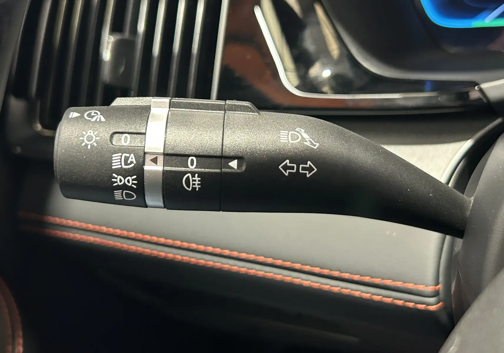 Gros plan sur la commande des phares et clignotants dans l'habitacle du BYD SEAL U, avec surpiqûres orange visibles.
