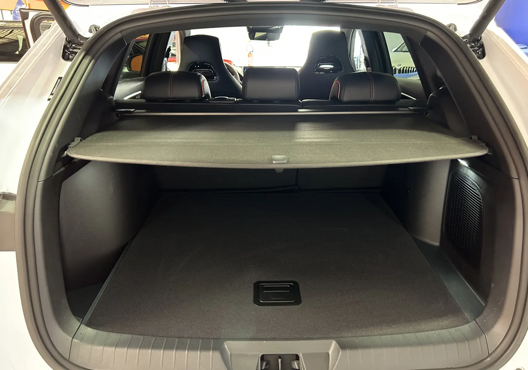 Vue arrière du coffre ouvert du BYD SEAL U blanc avec cache-bagages et sièges noirs visibles à l'intérieur.