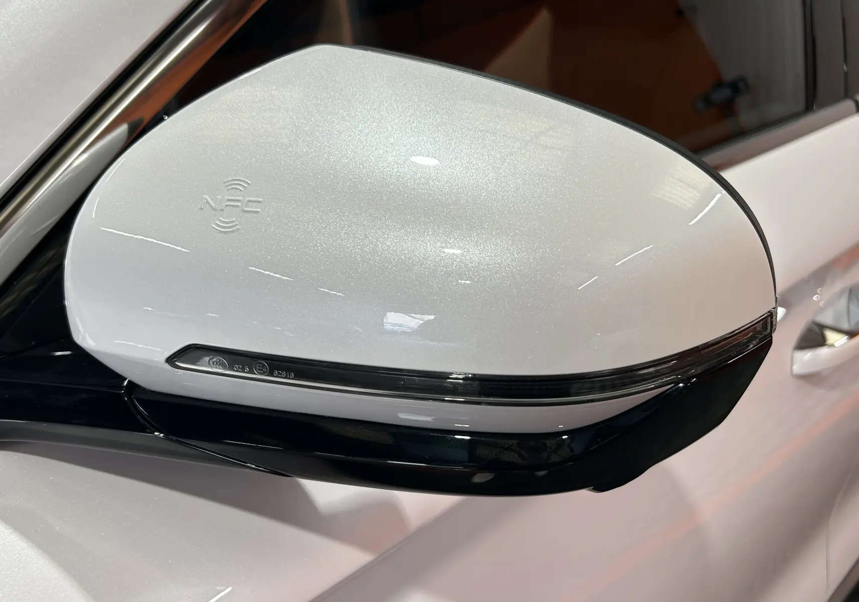 Gros plan sur le rétroviseur droit blanc nacré du BYD SEAL U 2025 avec clignotant intégré et logo NFC visible.