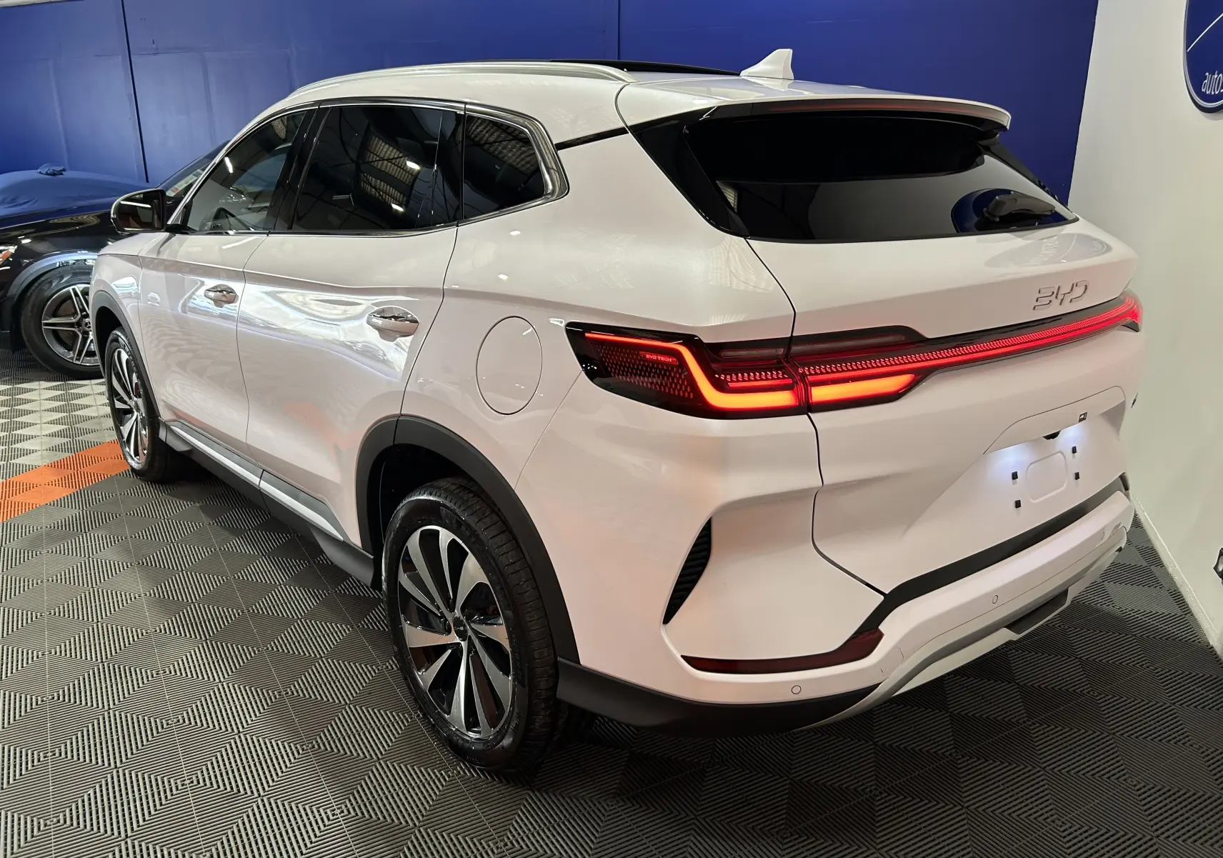 Vue 3/4 arrière droite du SUV BYD SEAL U blanc nacré avec feux arrière LED allumés dans un showroom.