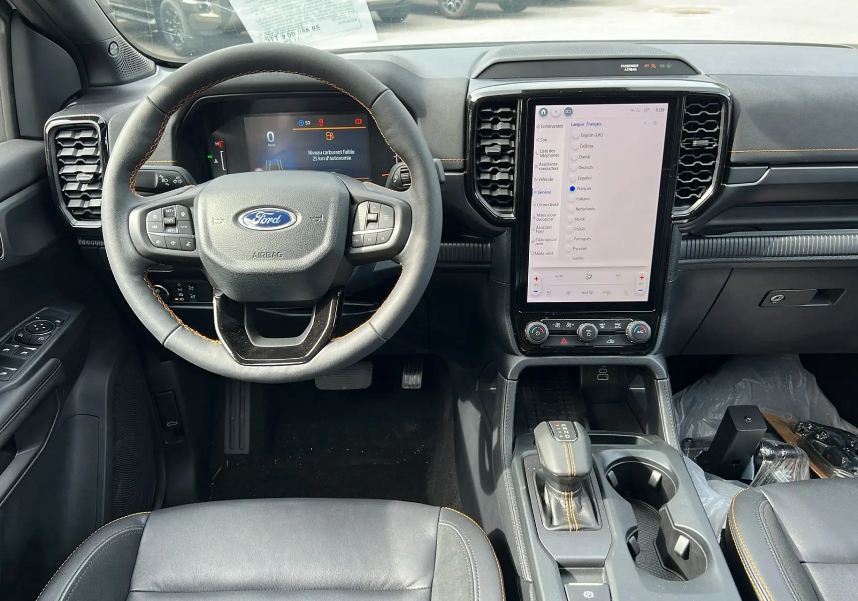 Vue intérieure avant du Ford Ranger 2026, tableau de bord noir avec écran tactile vertical et volant cuir multifonctions.