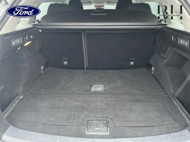 Coffre ouvert vu de l'arrière d'une Renault Mégane Break gris platine, espace de chargement plat et tapis noir.