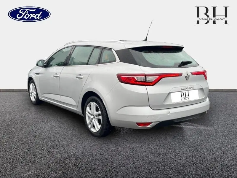 Vue 3/4 arrière droite d'une Renault Mégane Break gris platine avec feux arrière LED et barres de toit visibles.