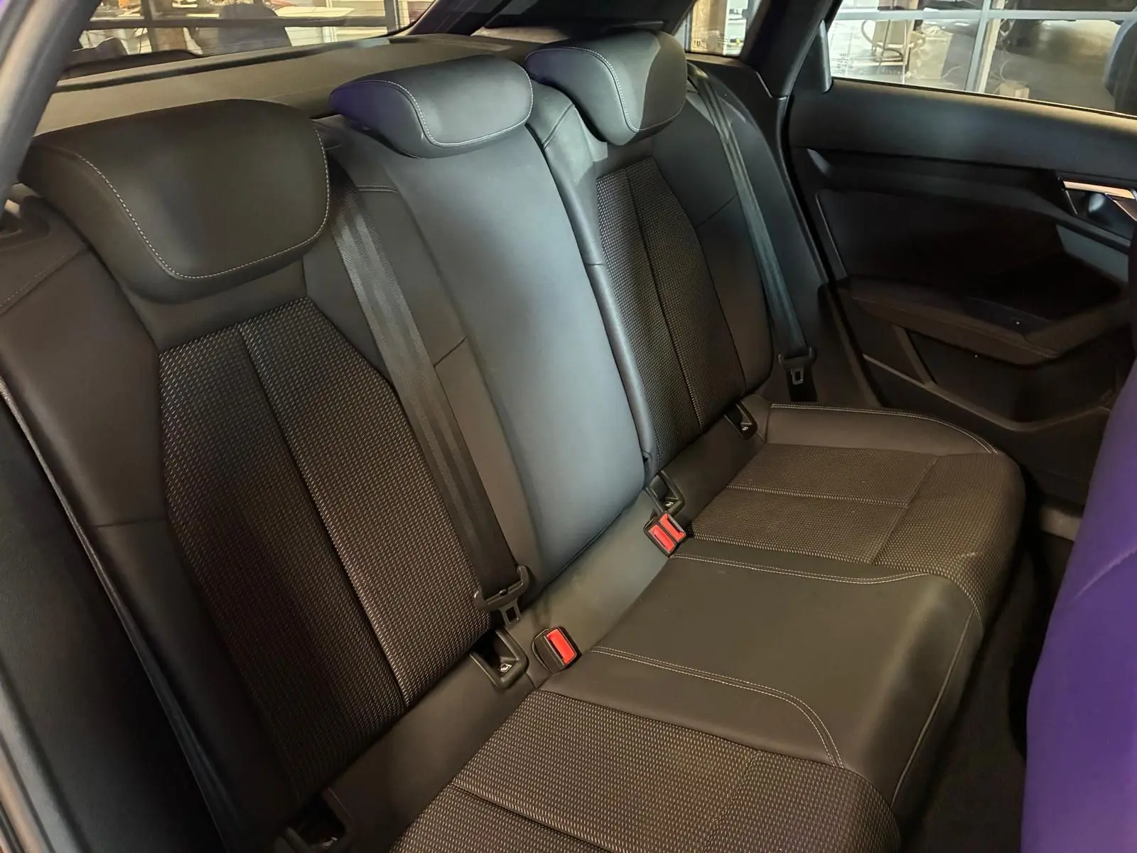 Vue intérieure du siège arrière noir de l'Audi A3 Sportback 2023 avec ceinture de sécurité et accoudoir central.