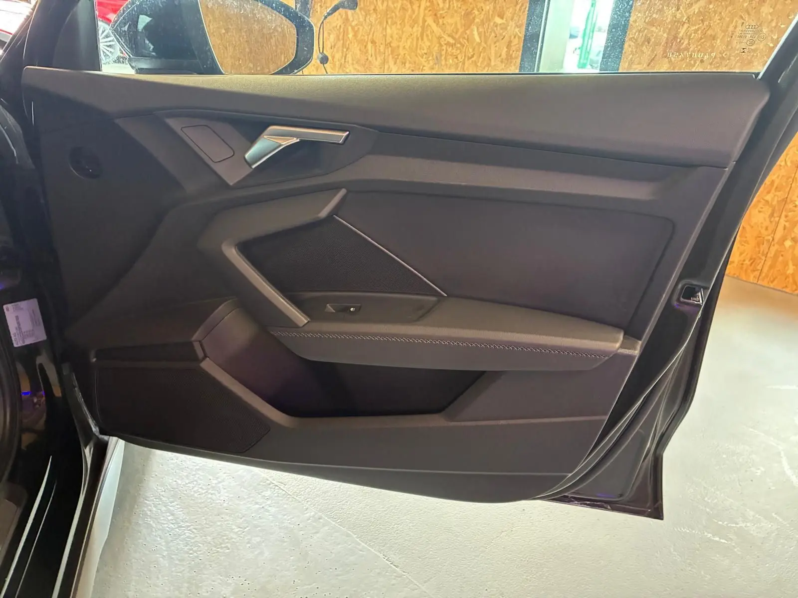 Vue rapprochée du panneau de porte côté gauche noir de l'Audi A3 Sportback 2023 avec accoudoir en similicuir et insert aluminium.