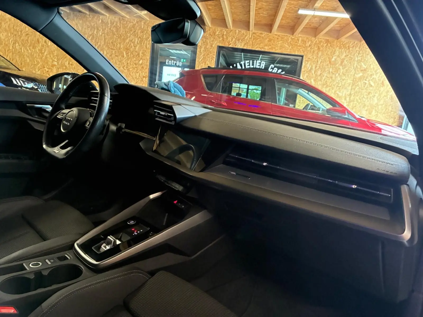 Vue intérieure côté conducteur de l’Audi A3 Sportback 2023 noire, avec tableau de bord moderne et volant multifonctions.