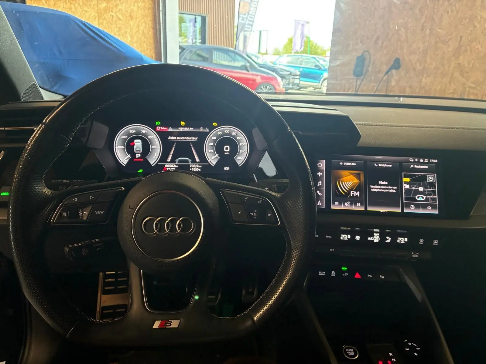 Vue intérieure centrée sur le volant cuir multifonctions S line et le tableau de bord numérique de l'Audi A3 Sportback 2023.