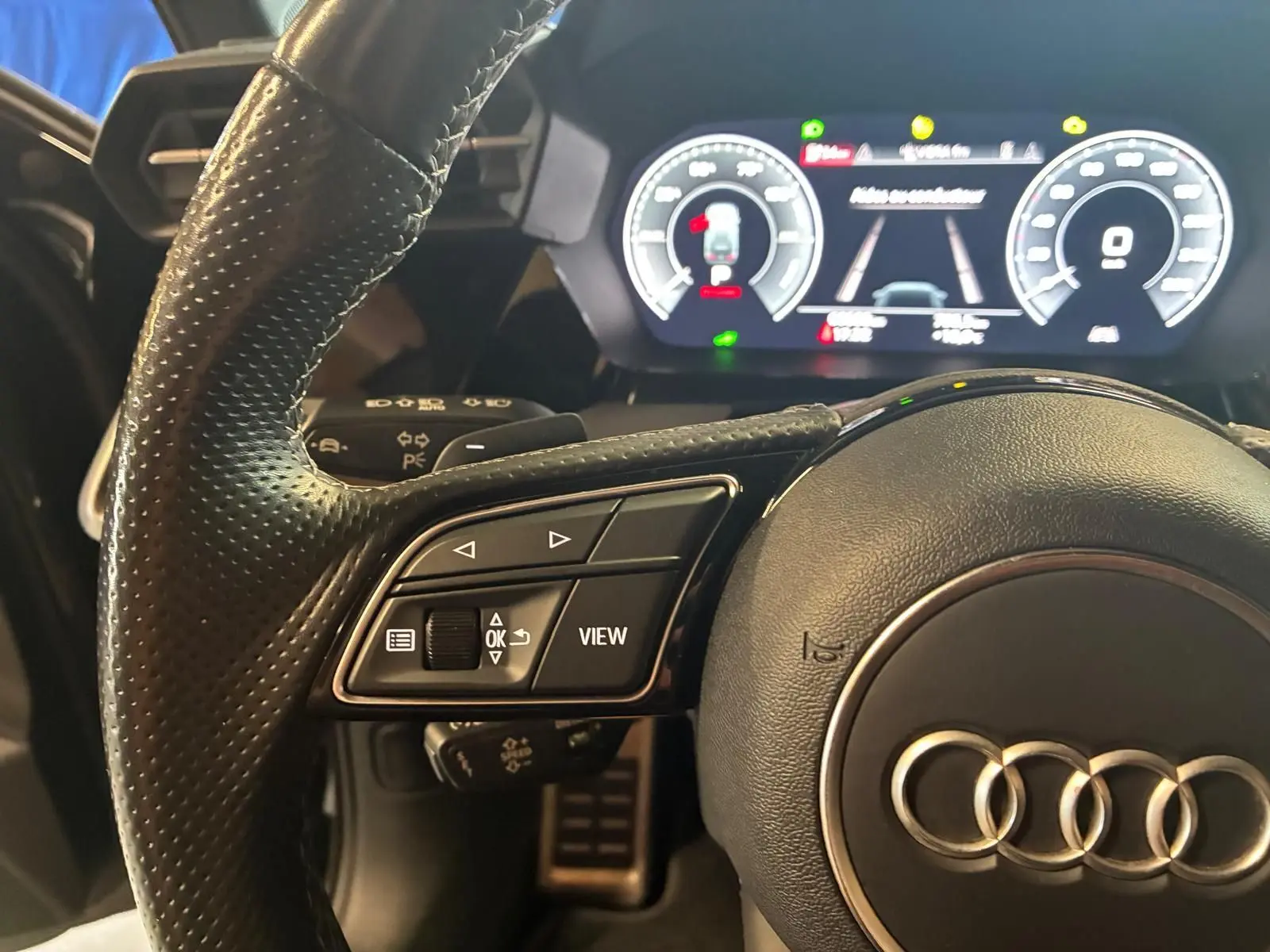 Gros plan sur le volant cuir multifonctions et le tableau de bord numérique éclairé de l'Audi A3 Sportback 2023.