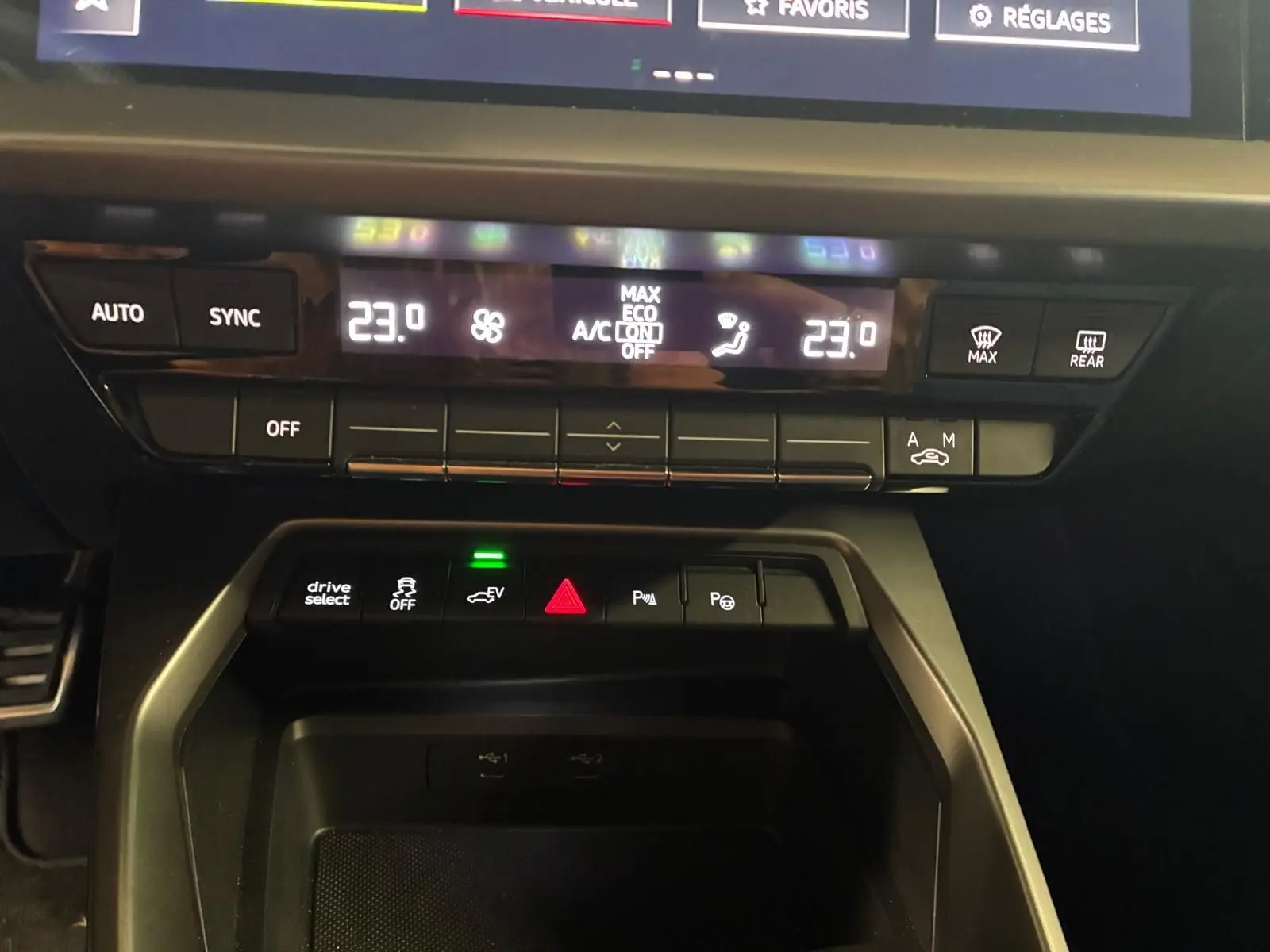 Vue rapprochée du tableau de bord noir de l'Audi A3 Sportback 2023, montrant la climatisation digitale et les commandes centrales.