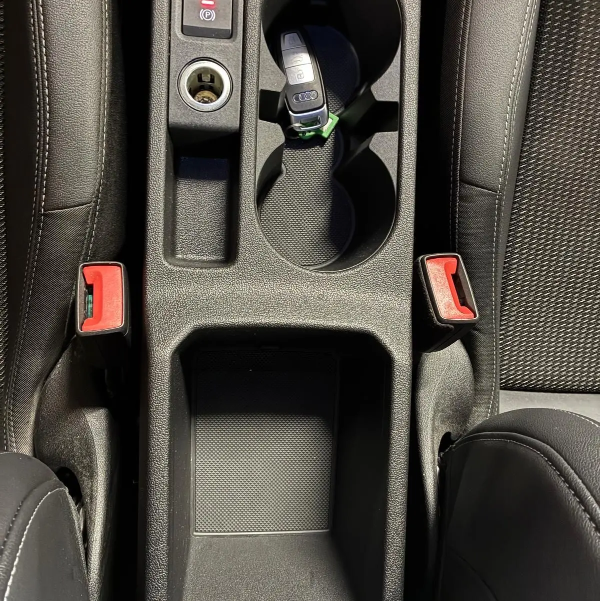 Vue plongeante sur la console centrale noire de l'Audi A3 Sportback avec clé et porte-gobelets intégrés.