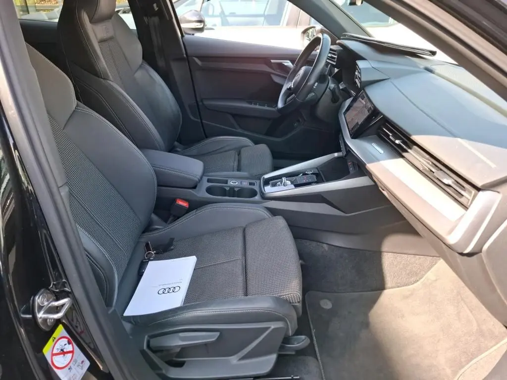 Vue intérieure côté conducteur de l'Audi A3 Sportback noire 2023, sièges sport en cuir et tableau de bord moderne.