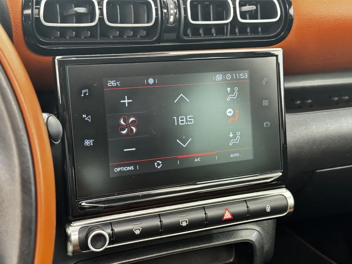 Écran tactile central affichant la climatisation à 18,5°C, entouré de garnitures noires et tableau de bord marron du Citroën C3 Aircross.