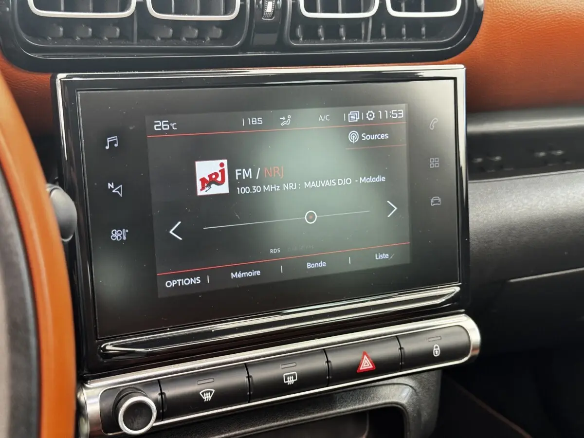 Écran tactile central de la Citroën C3 Aircross 2020, affichant la radio FM NRJ, avec tableau de bord noir et orange.