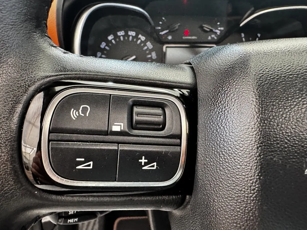 Gros plan sur les commandes vocales et volume du volant cuir noir de la Citroën C3 Aircross 2020.