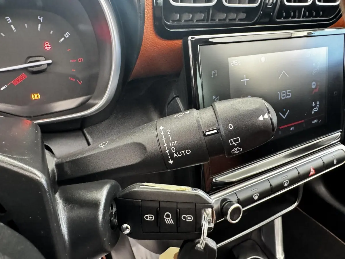 Gros plan sur la commande d’essuie-glace et la clé dans le contacteur d’un Citroën C3 Aircross noir, tableau de bord et écran tactile visibles.