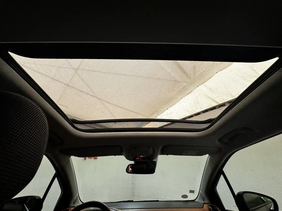Toit panoramique ouvert vu de l'intérieur avant d'une Citroën C3 Aircross noire, avec rétroviseur central visible.